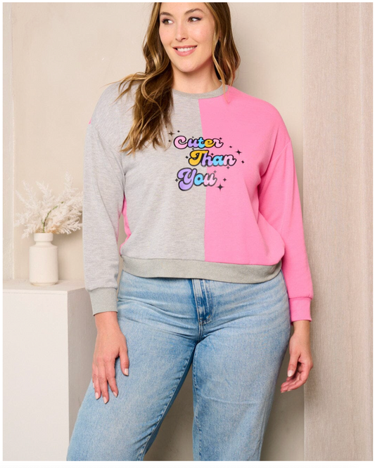 Woman wearing a colorful sweatshirt with text and light blue jeans indoors.