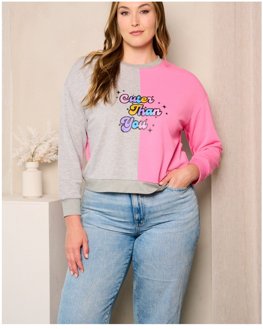 Woman wearing a colorful sweatshirt with text and jeans against a neutral background