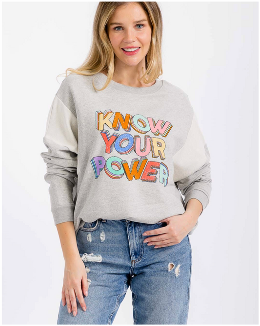 Woman wearing a gray sweatshirt with 'Know Your Power' text in colorful letters on a white background