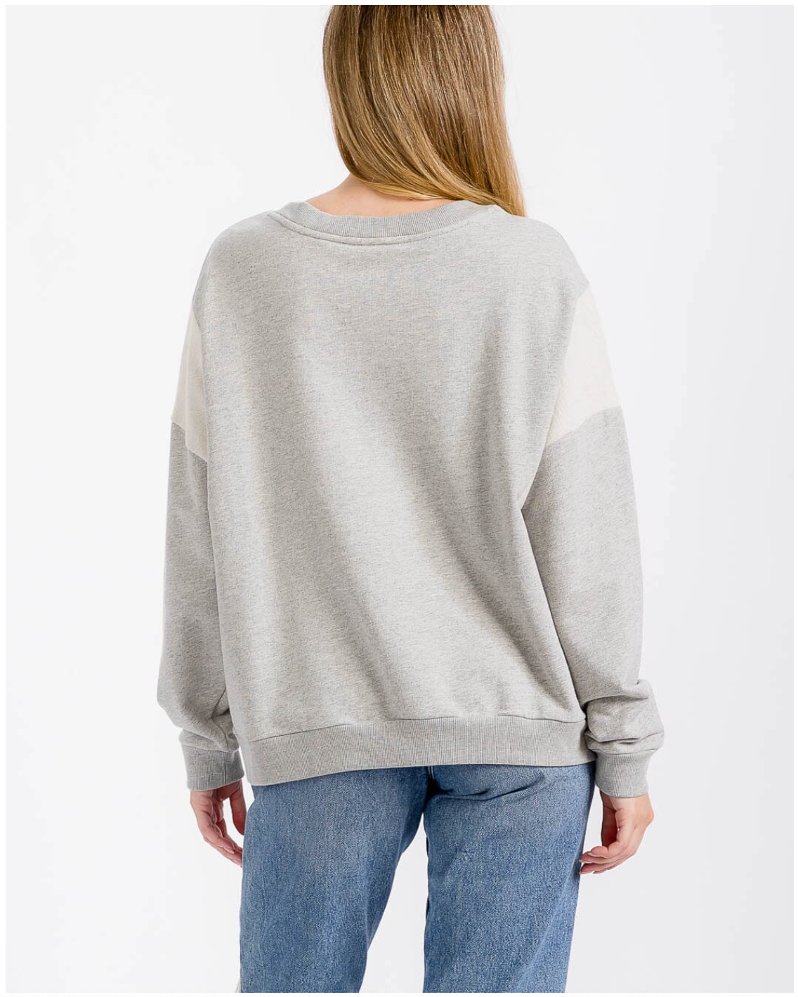 Person wearing a gray sweatshirt and blue jeans on a white background