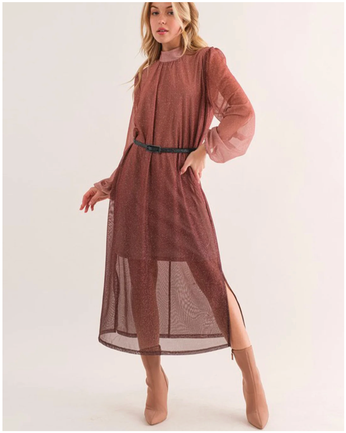 Woman wearing a long, sheer brown dress with a belt on a white background