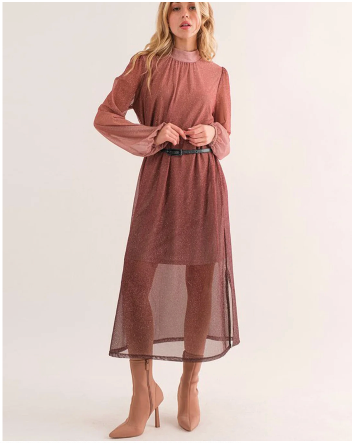 Woman wearing a long-sleeve, high-neck dress with sheer panels on a white background